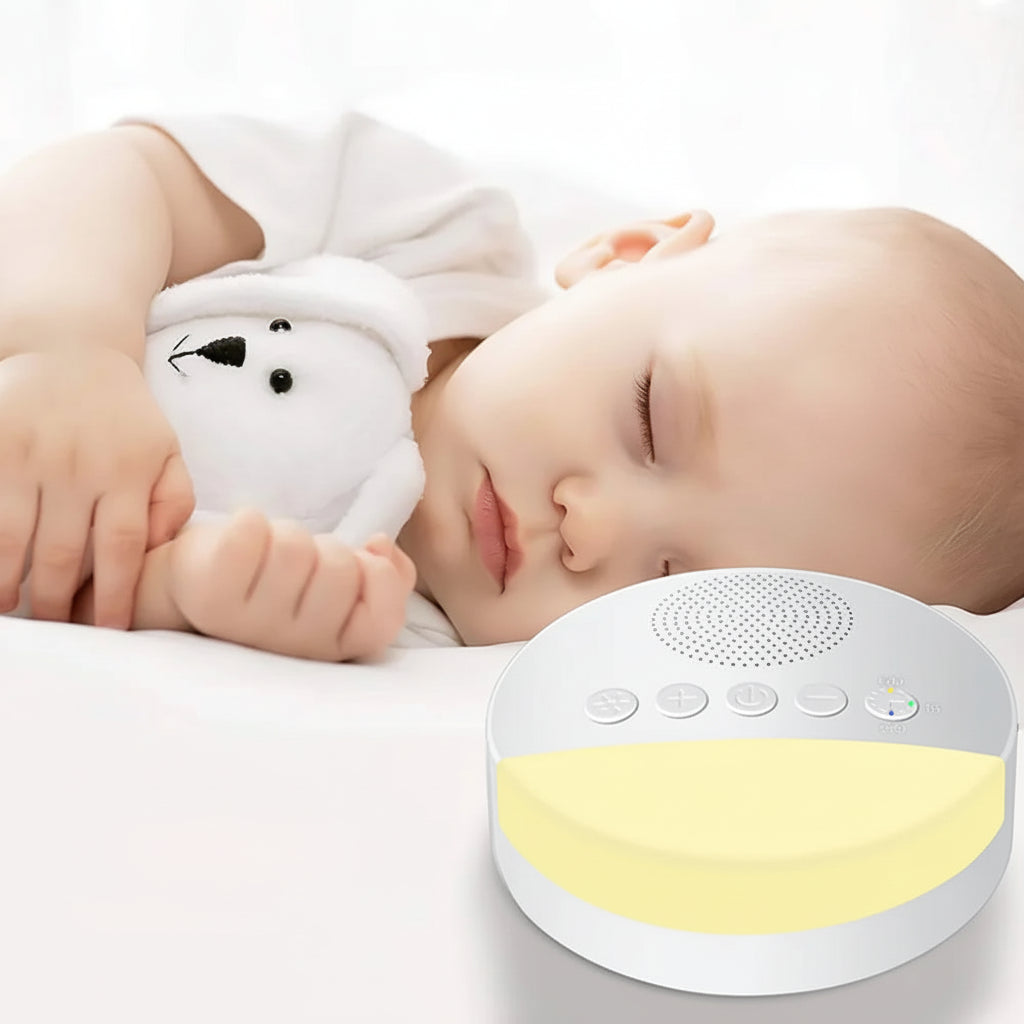 Sleeping baby cuddling plush toy beside night light sound machine on white bedding